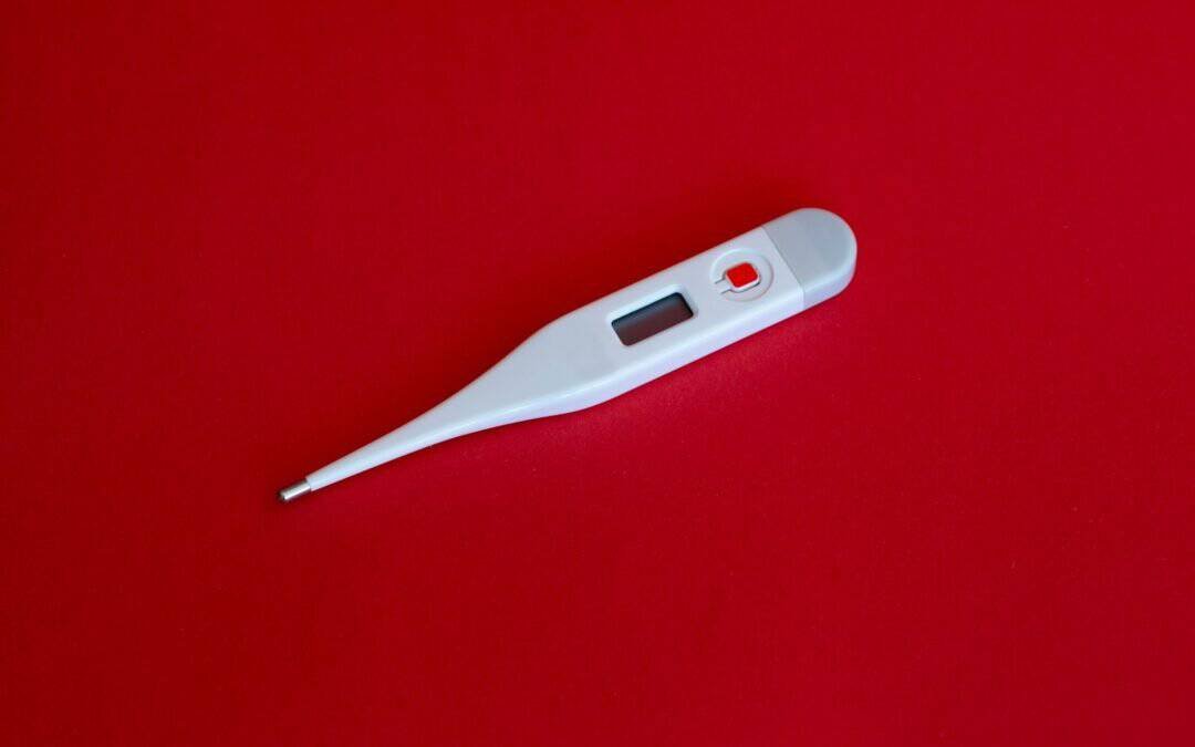 white thermometer on red surface for malaria